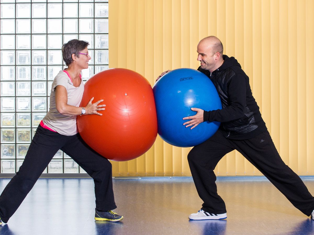 Eine Frau und ein Mann drücken sich mit bunten Bällen voneinander weg 