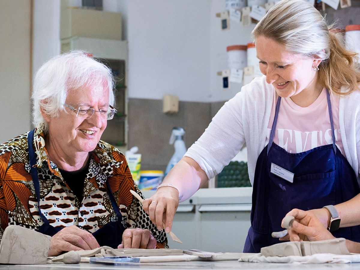 Ergotherapeutin zeigt Patient das Arbeiten mit Ton