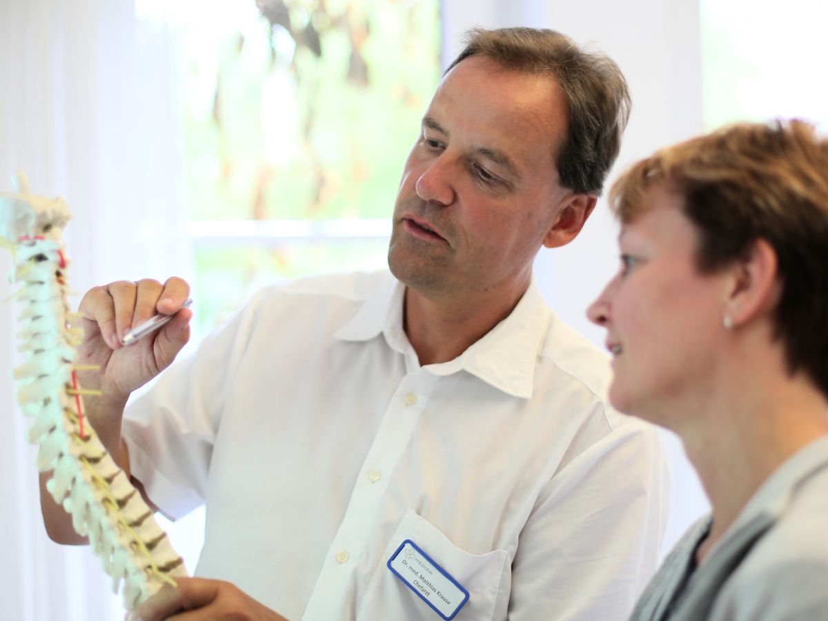 Zwei Personen die sich ein Wirbelsäulen Modell anschauen 