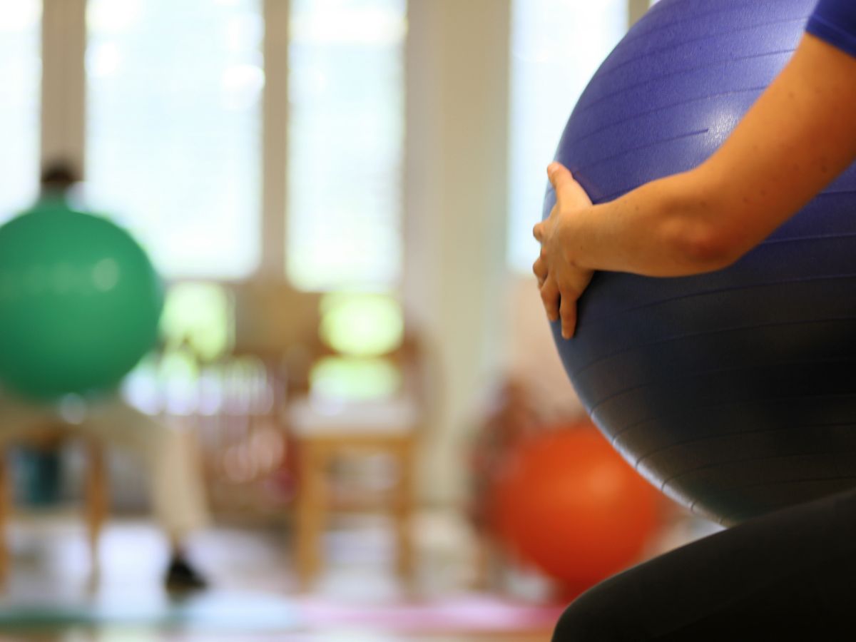 Eine Person die sitzt und einen Gymnastikball in der Hand hält 