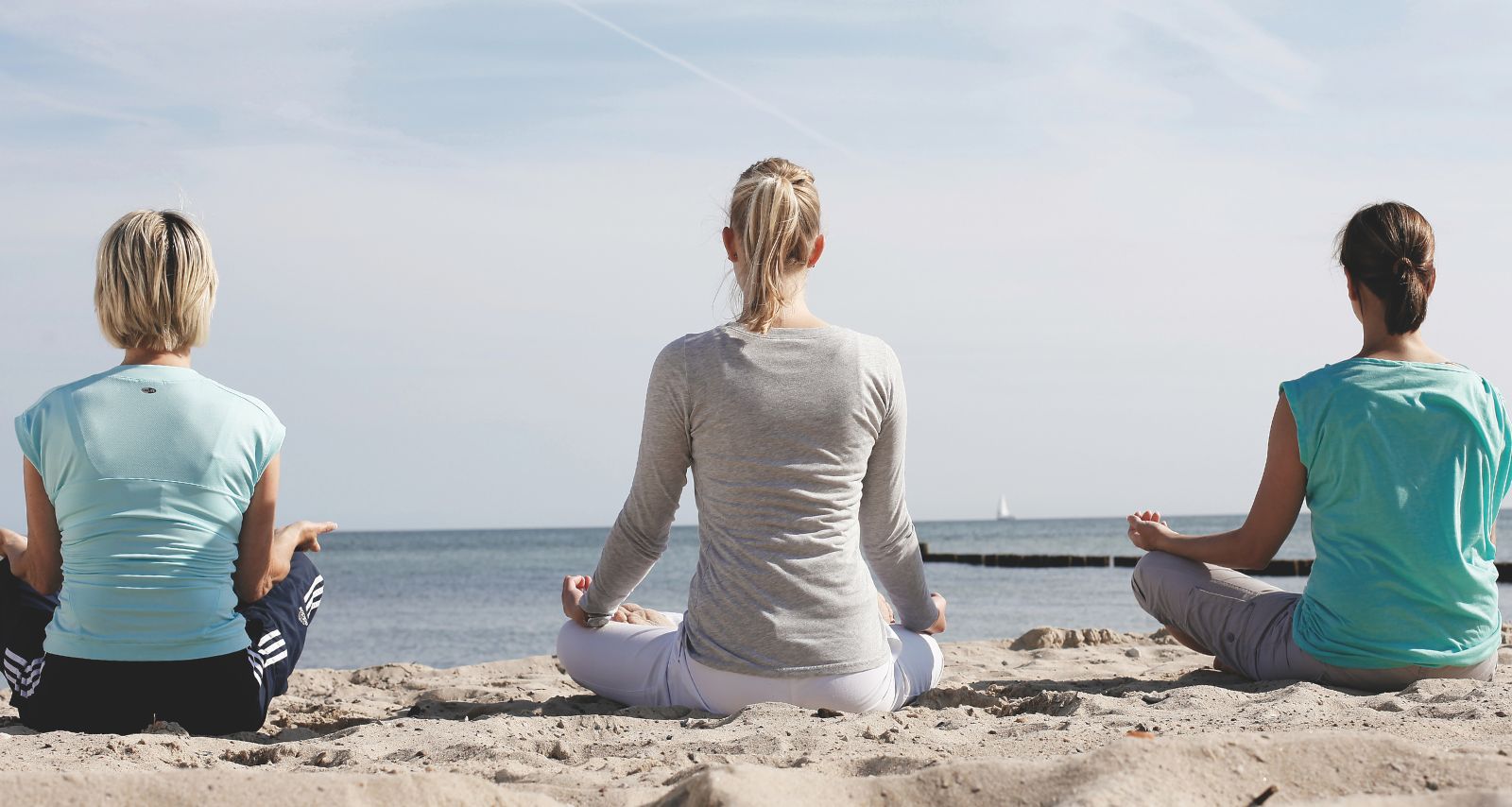 Drei Frauen sitzen im Schneidersitz und meditieren 