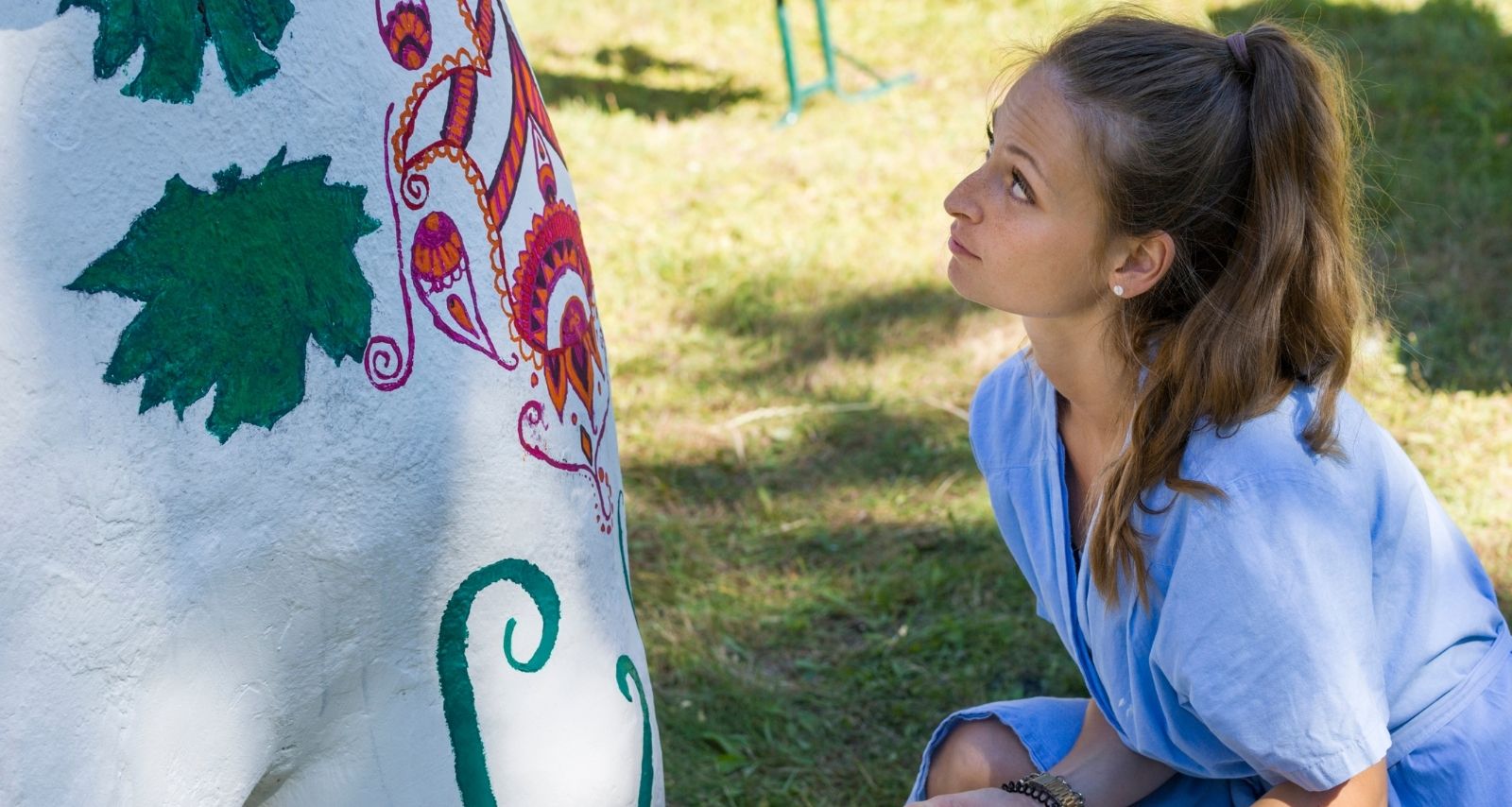 Eine Frau schaut einen bemalten Stein an 