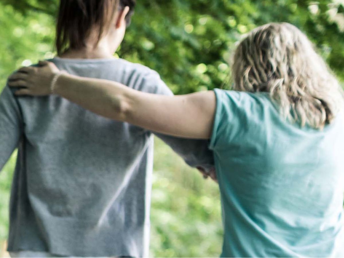 Therapeutin unterstützt Patientin beim Gehen auf dem Barfusspfad