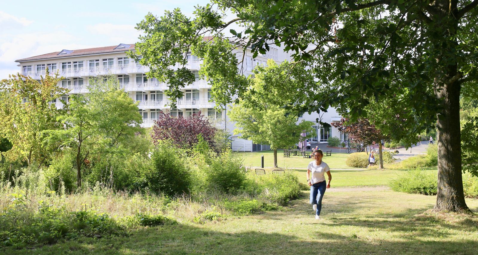 Gartenanlage der Einrichtung und eine Frau die spazieren geht 