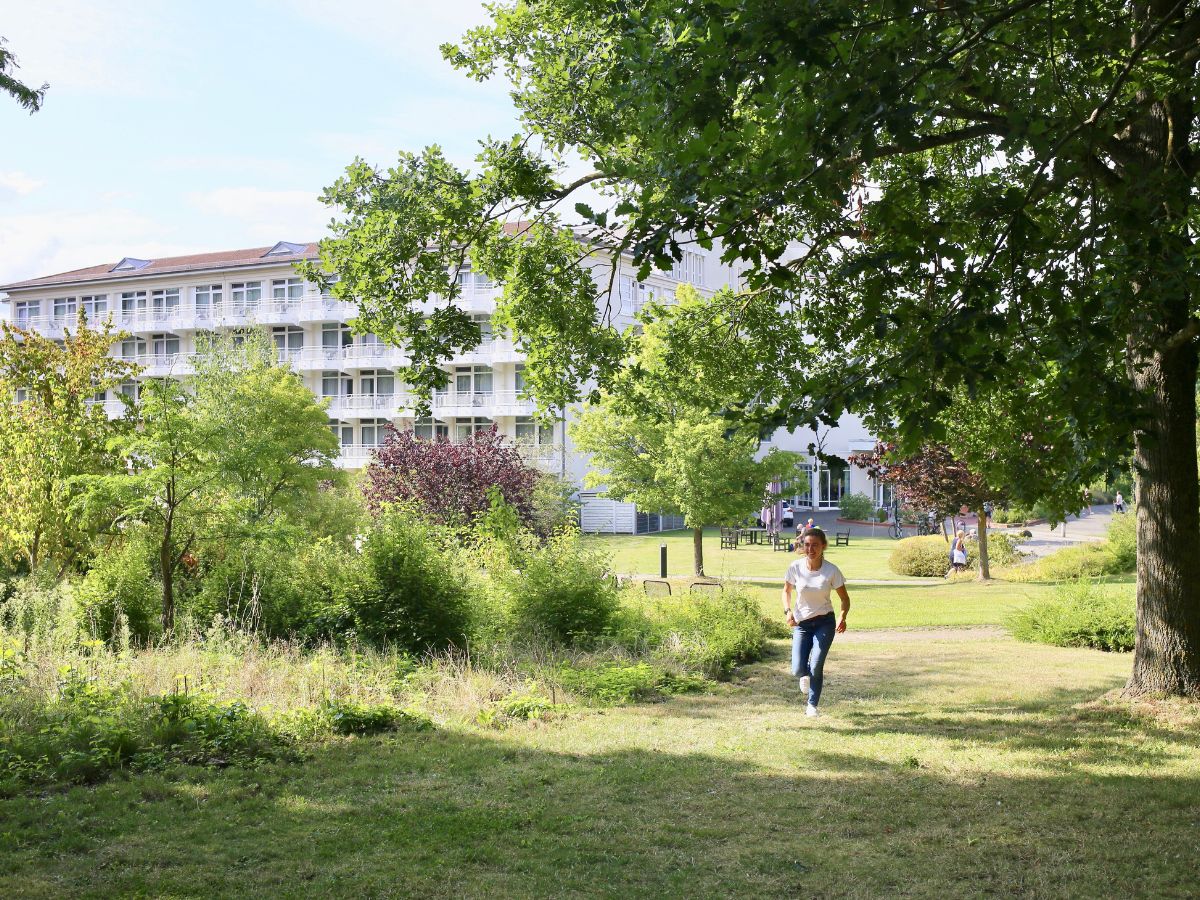 Gartenanlage der Einrichtung und eine Frau die spazieren geht 
