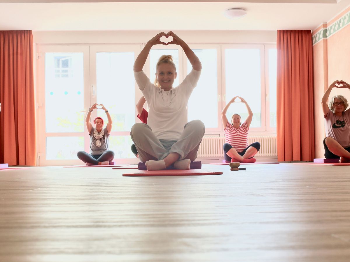 Person die Yoga betreiben und Herz mit den Händen formen 