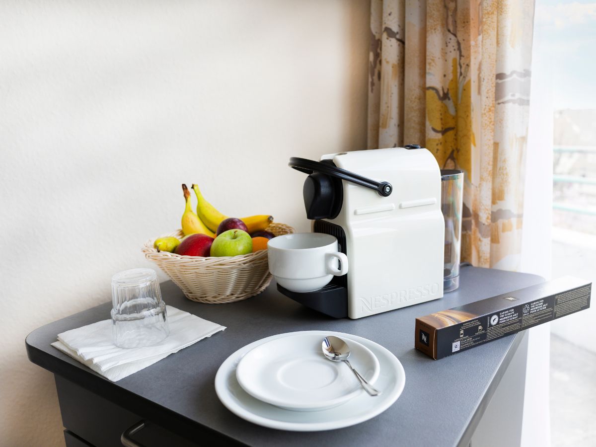 Kaffeemaschine, Teller und Obst stehen auf dem Kühlschrank