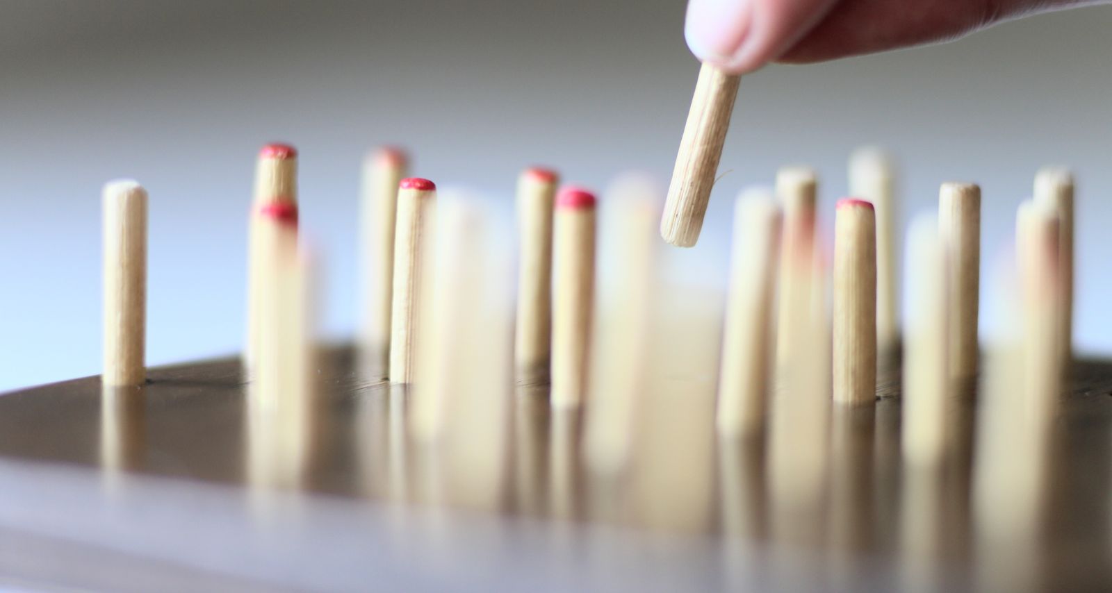 Eine Person die nebeneinander Holzstäbchen aufstellt 