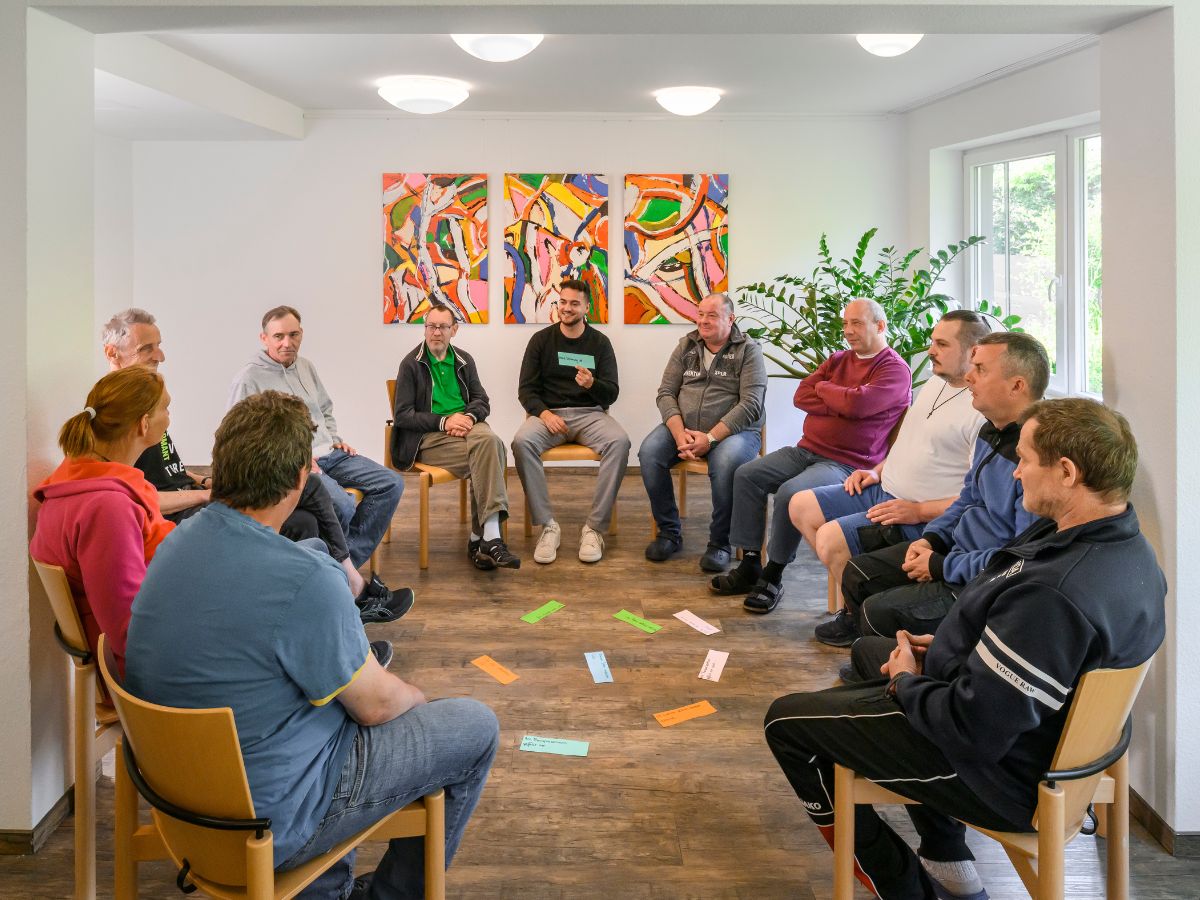 Eine Gruppe von Personen sitzt im Raum im Kreis 