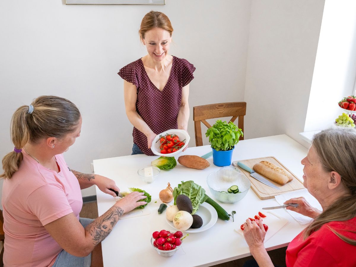 Eine Frau zeigt den anderen Frauen das Essen auf dem Tisch