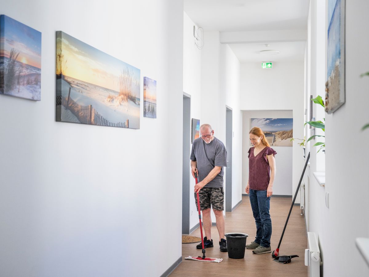 Ein Mann putzt den Boden und eine Frau steht daneben