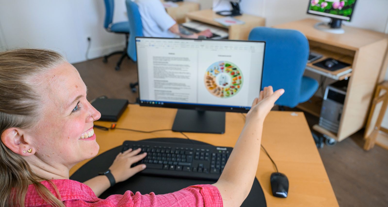 Eine Frau zeigt etwas auf dem Monitor