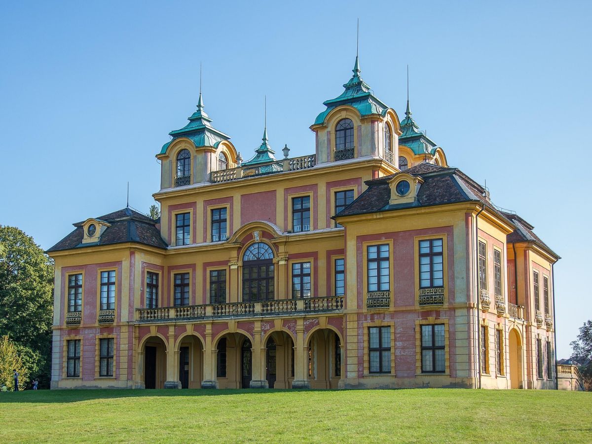 Gelbes Schloss Favorite in Ludwigsburg mit zwei Türmen und einer Rasenfläche im Vordergrund