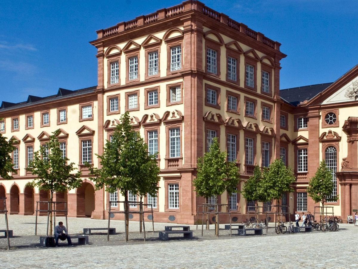 Rosa und helle Schlossfassade in Mannheim mit hohen Fenstern und gepflastertem Platz davor