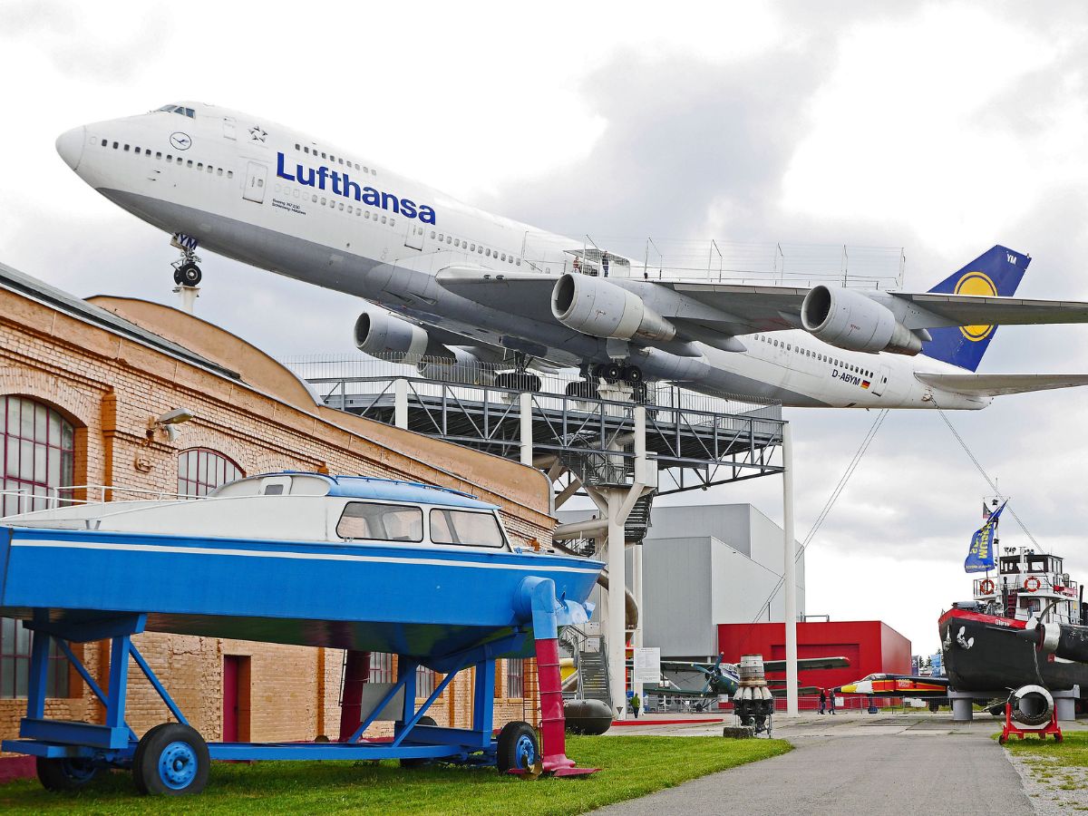 Lufthansa-Boeing 747 auf einem Stahlgerüst im Technik Museum Speyer, darunter ein blaues Boot und ein Weg