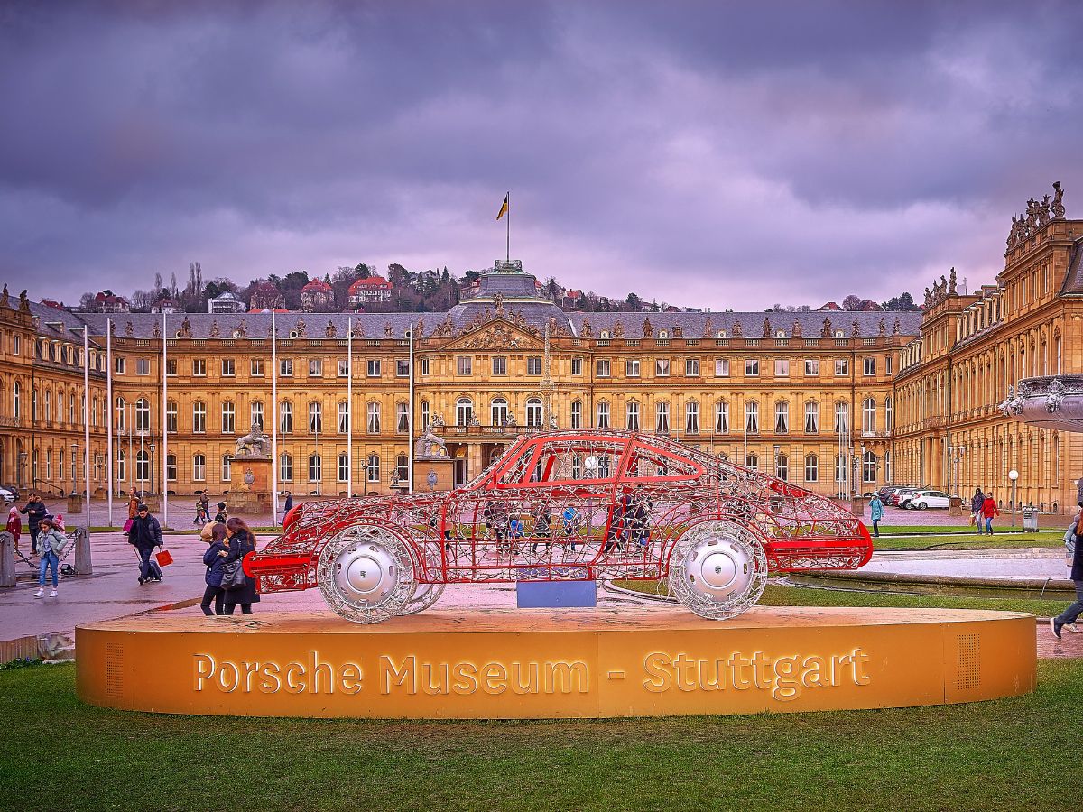 Rote Drahtkonstruktion eines Porsche auf dem Stuttgarter Schlossplatz, dahinter das Neue Schloss und rechts ein Brunnen