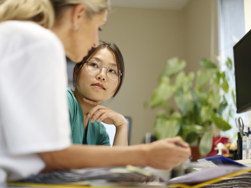 Zwei Mitarbeiterinnen schauen sich Unterlagen an und besprechen sich
